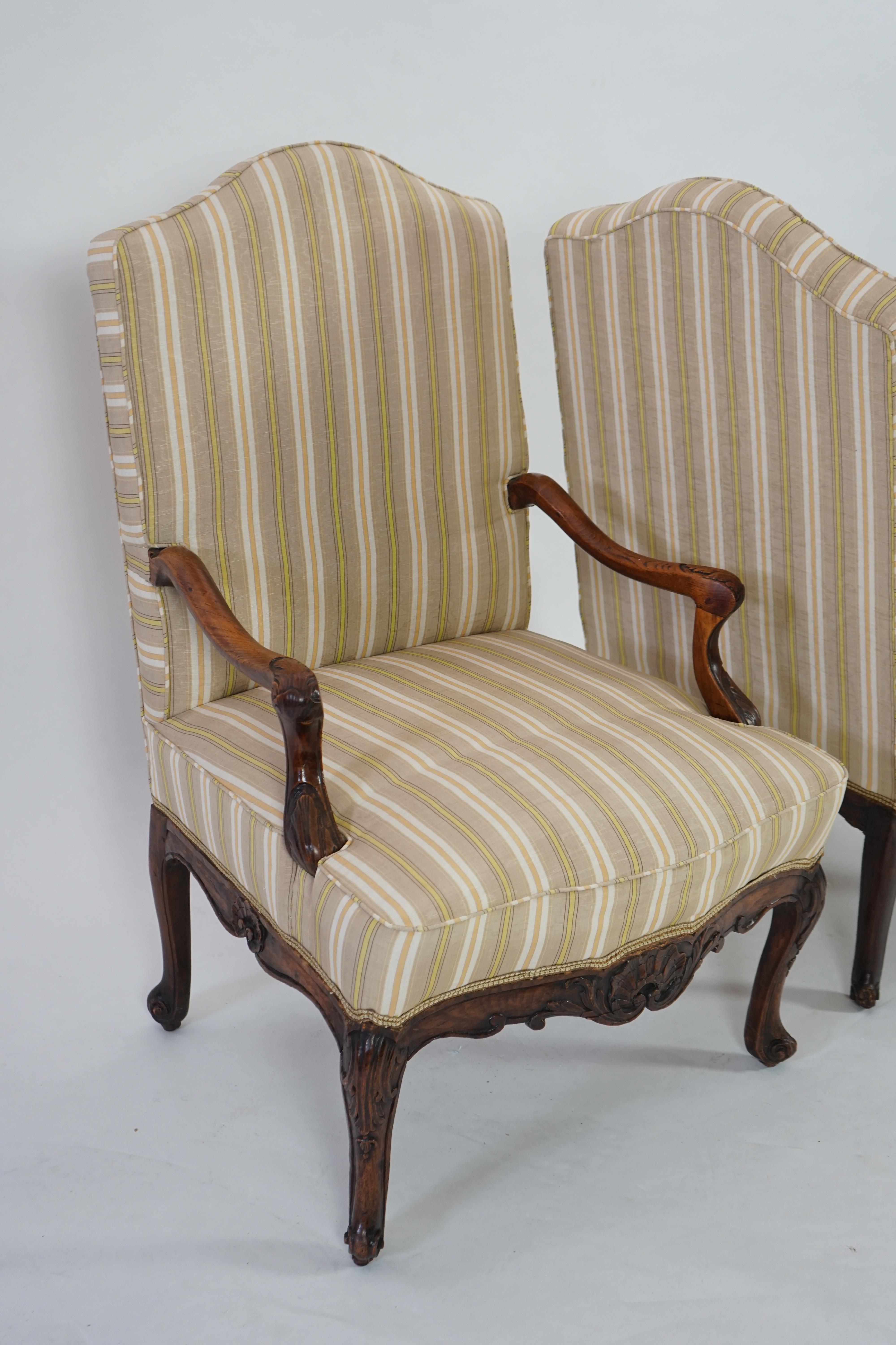 A pair of Louis XVI walnut fauteuils with upholstered backs and seats and foliate carved arms and underframes, on cabriole legs, width 67cm, depth 76cm, height 104cm. Condition - fair